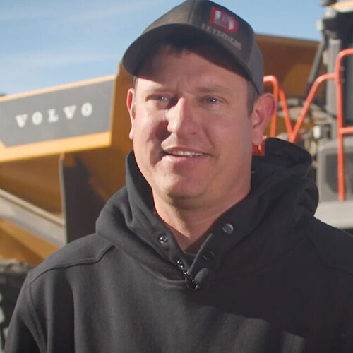 Chris Guins smiling in front of a Volvo A40 articulated haul truck.